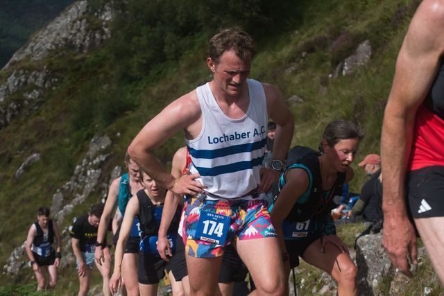Dave in a Lochaber AC vest, hands on hips, climbing a steep hill race