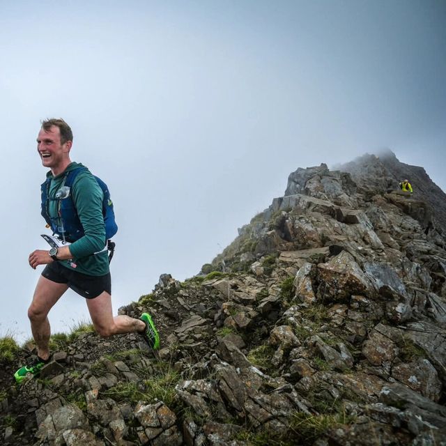 Running up a rocky ridge in the clouds, grinning