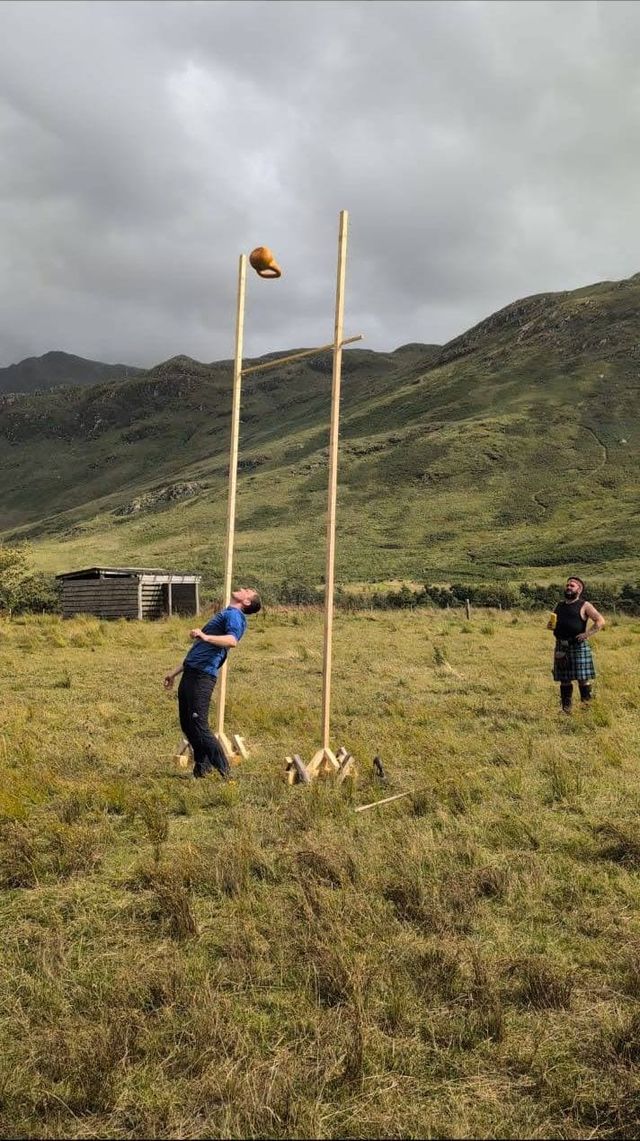 Dave throwing a kettlebell over a high bar between two posts