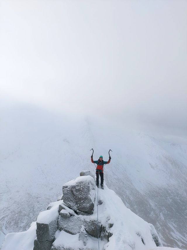 Ice axes raised on a snowy summit in the clouds